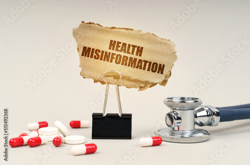 Near the stethoscope are pills and a clip with a cardboard sign - health misinformation photo