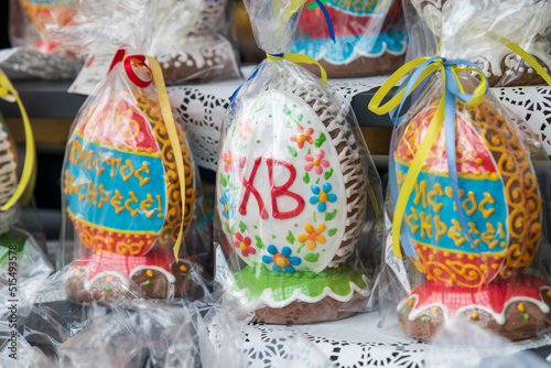 Group of colorful packed egg shaped Easter Pryaniks (russian gingerbread with honey) stands on store shelfs. Selective focus. Festive baking theme. photo