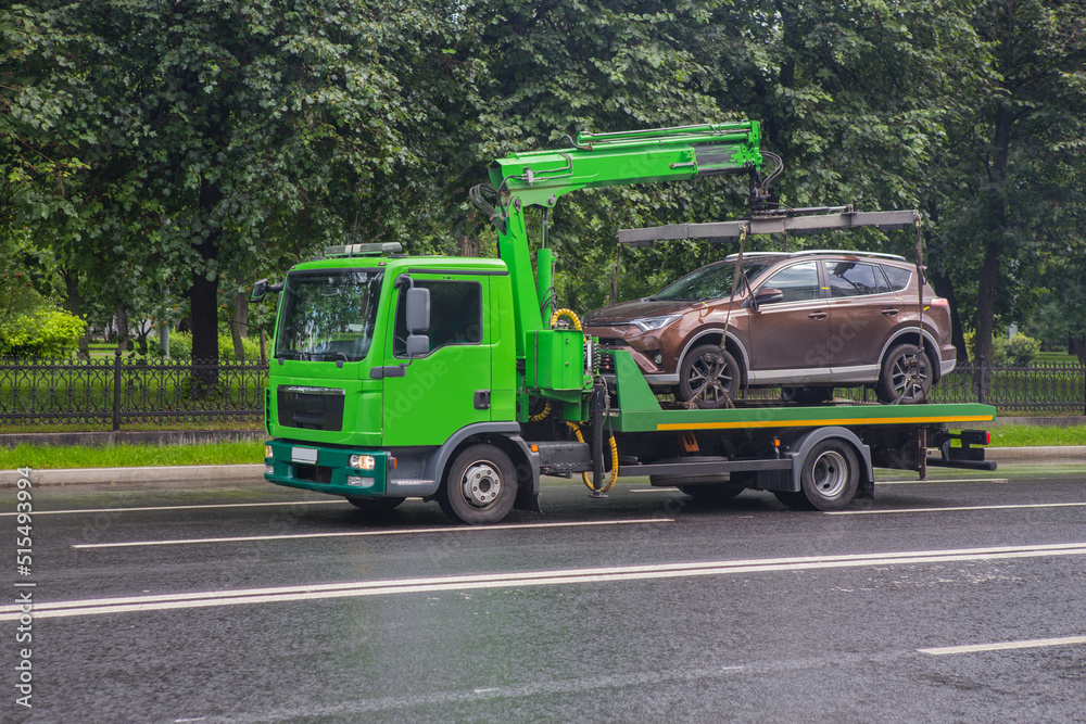 Tow truck transports a car down the street