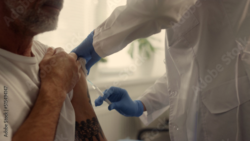 Mature patient getting vaccine dose in clinic closeup. Doctor vaccinating man.