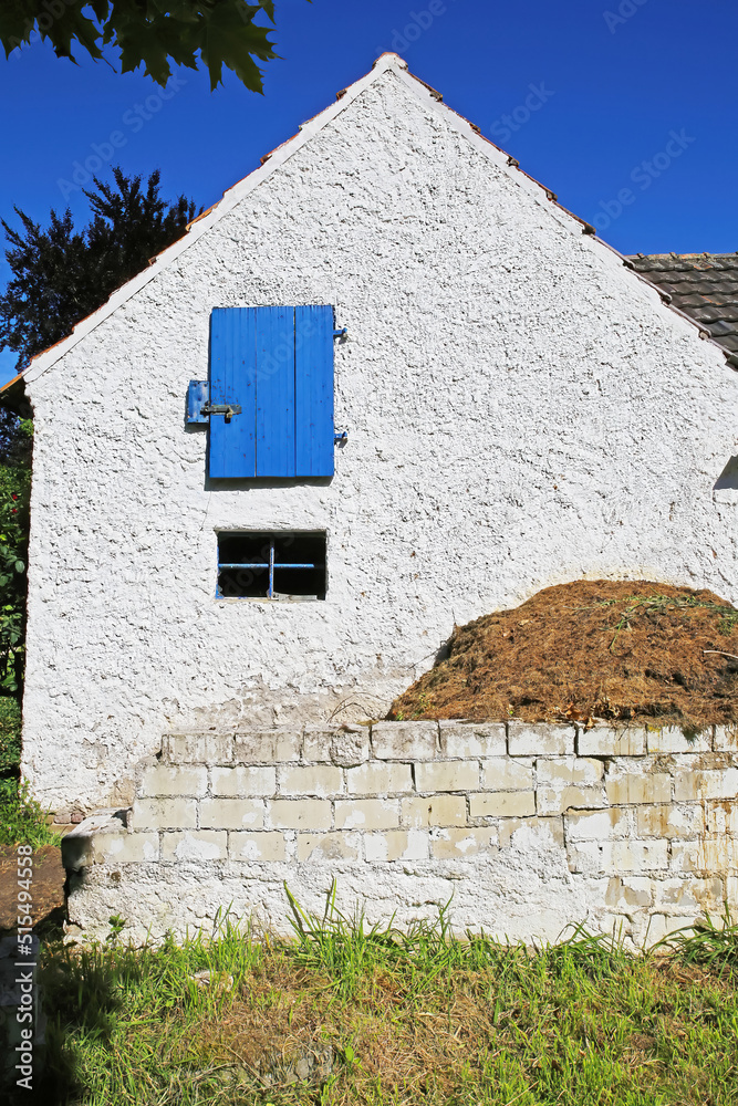 Old isolated white german country farm house facade, blue window shutter, dung heap - Wachtendonk (lower rhine area, Niederrhein), Germany