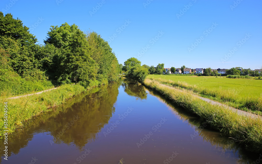 Typical beautiful lower rhine (Niederrhein) rural summer landscape, river niers, blue summer sky, village, green forest, cycle path - Wachtendonk, Germany Typical beautiful lower rhine (Niederrhein) rural summer landscape, river niers, blue summer sky, village, green forest, cycle path - Wachtendonk, Germany