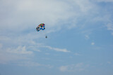 Parasailing, Flying On A Parachute Behind A Boat On A Summer Holiday By The Sea In The Resort, Multi-colored parachute with man on background of sea and blue sky. Copy space.