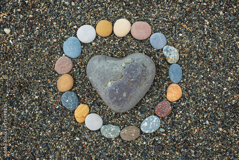 Heart shaped sea stone pebble on sandy beach Heart shaped sea stone pebble on sandy beach