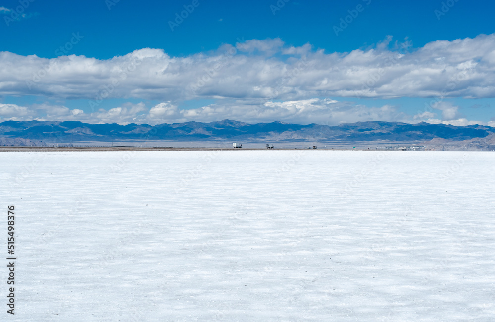 Glittering white Salt Flats in Utah, United States with cars and trucks on a highway in the distance. Glittering white Salt Flats in Utah, United States with cars and trucks on a highway in the distance.