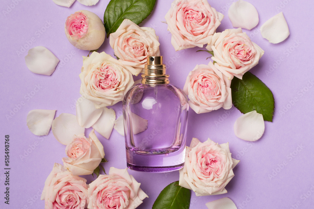 Bottle of perfume with rose flowers on color background, top view