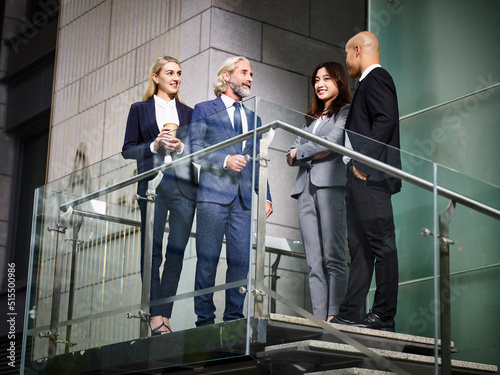 team of multiethnic business people standing talking chatting discussing in modern office building