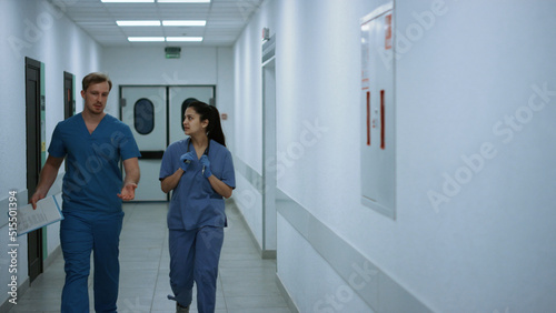 Doctors walking down corridor discussing diagnose. Medics hurrying to operation.