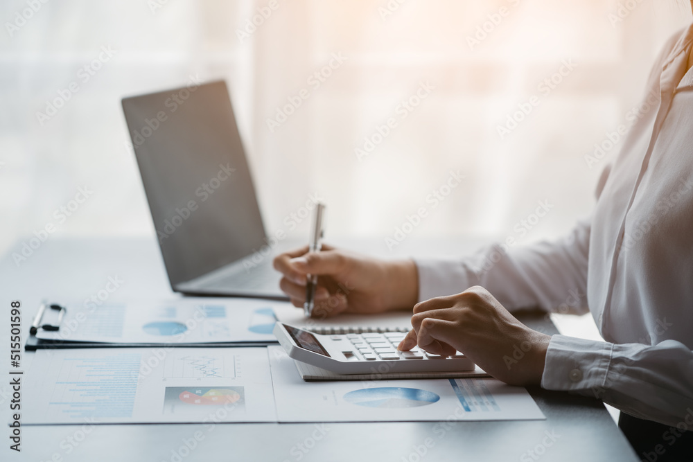 Close-up hands of business people working in office with laptop, paperwork and calculator on table Close-up hands of business people working in office with laptop, paperwork and calculator on table
