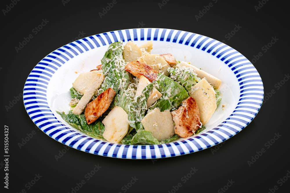 Caesar salad with chicken, Romano salad, with a sauce of blue cheese. On a dark background, isolated. Caesar salad with chicken, Romano salad, with a sauce of blue cheese. On a dark background, isolated.