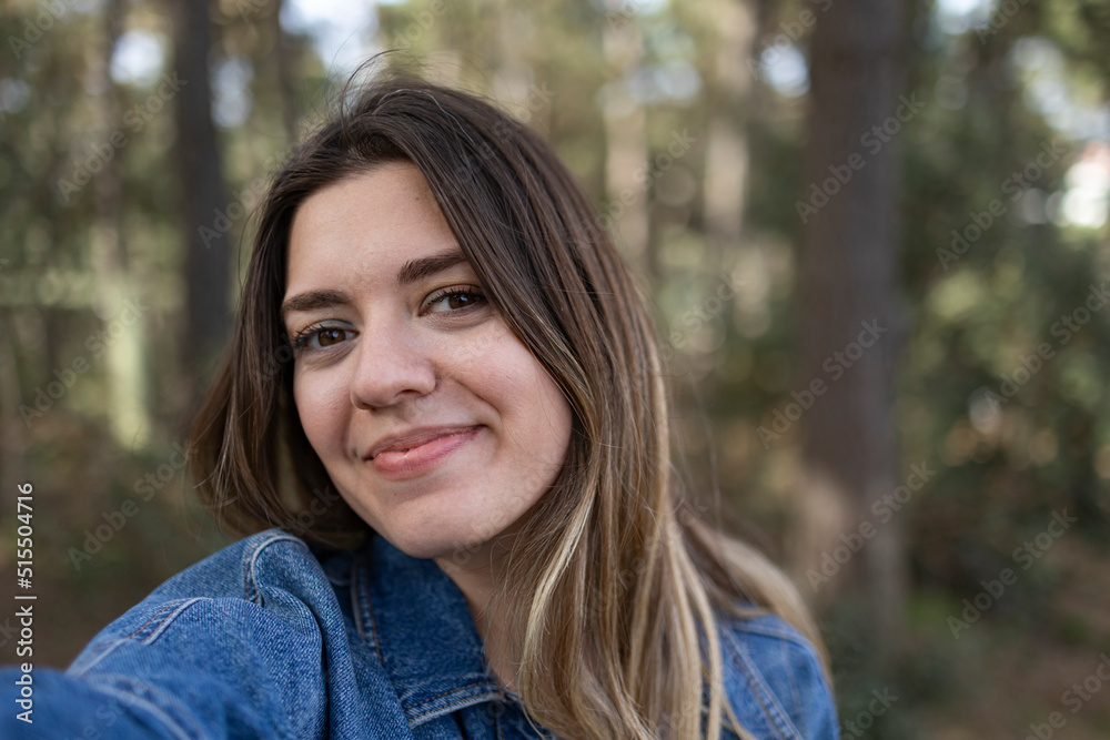 Happy young influencer woman taking selfie at forest. She will share on social media. She is smiling. Nature, travel, walking concept. Happy young influencer woman taking selfie at forest. She will share on social media. She is smiling. Nature, travel, walking concept.