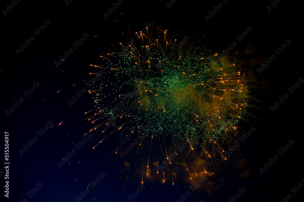 Bright fireworks with a green center with orange sparks flying towards the background of the night sky. High quality photo Bright fireworks with a green center with orange sparks flying towards the background of the night sky. High quality photo
