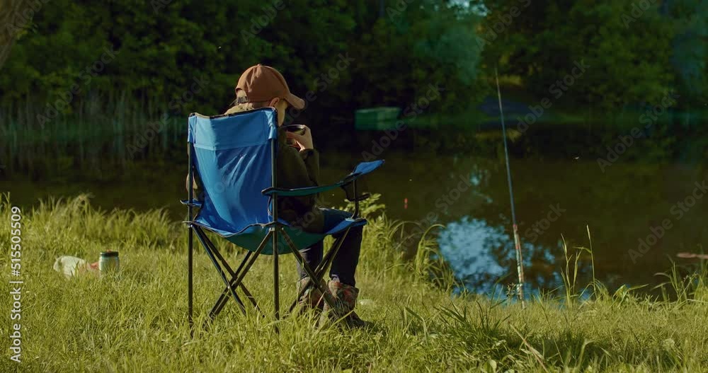 boy is drinking tea and waiting bite, angling by fishing rod in beautiful lake, 4K, Prores boy is drinking tea and waiting bite, angling by fishing rod in beautiful lake, 4K, Prores