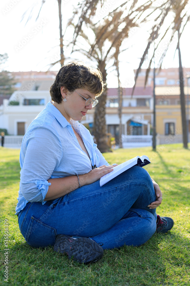 Woman Reading While Sitting on Green Grass Near the Sea Woman Reading While Sitting on Green Grass Near the Sea