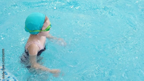 Little girl learning to swim with mother in big sport pool. Swimming school for small children. Healthy kid enjoying active lifestyle. Preschooler practicing with foam pad and noodle. © Dilya