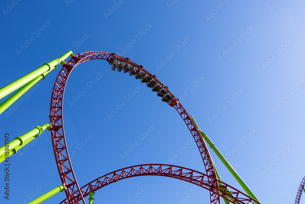 Roller coaster with speeding trolleys against blue sky Roller coaster with speeding trolleys against blue sky