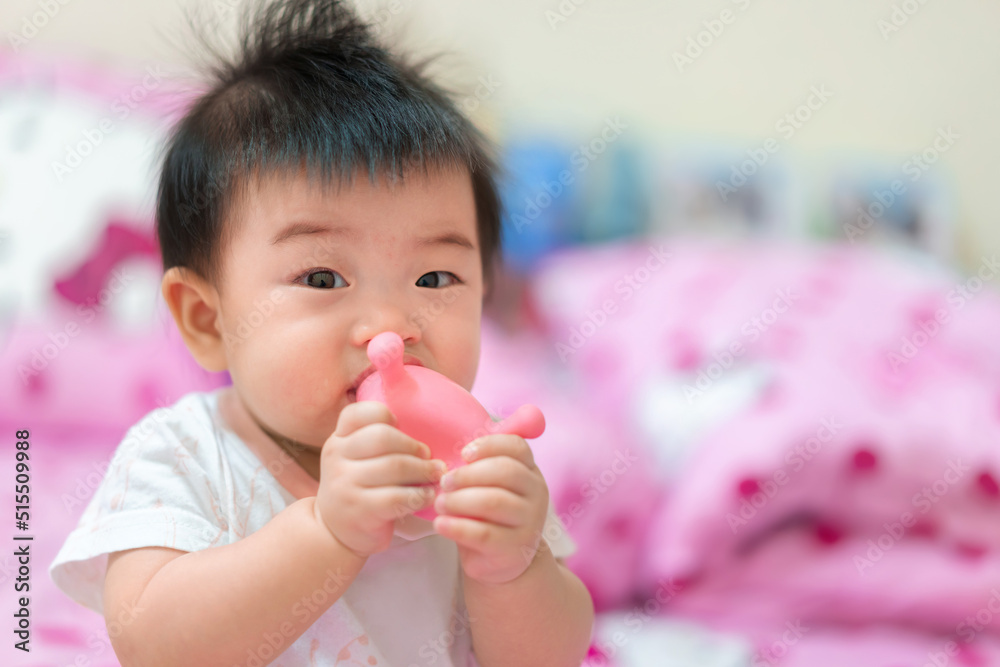 Asian Infant girl biting teether, baby growing first tooth. Asian Infant girl biting teether, baby growing first tooth.