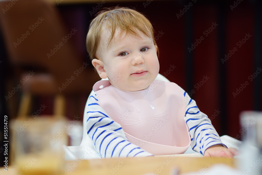 Mother feeding cute baby boy healthy eating nutrition food in public