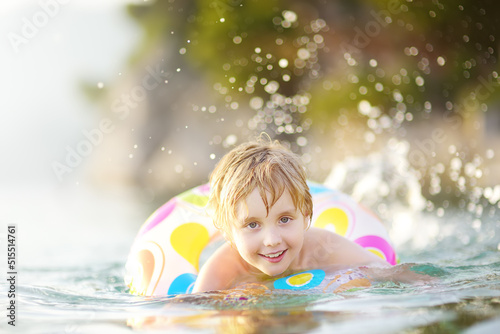 Little boy swimming with colorful floating ring in sea on sunny summer day. Cute child playing on beach. Family and children s resort holiday during summer vacations.
