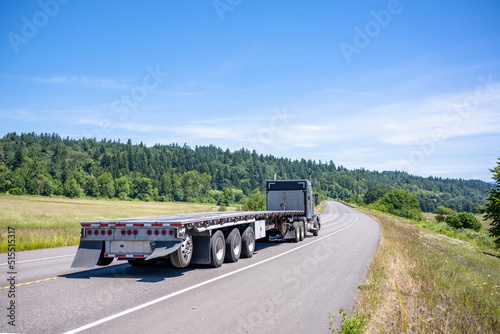 Quadro su tela Black classic big rig semi truck tractor transporting empty flat bed semi traile