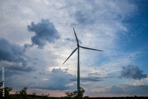 Selective blur on a windmills in the fields of Voivodina, in Serbia, during a sunny night, atdusk. This windfarm, made of wind turbines, is aimed at producing renewable energy and green electricity photo