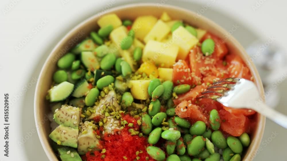 Poke bowl with salmon, rice, avocado, edamame beans, cucumber and radish in gray bowl. Hawaiian ahi poke bowl, gray background. Poke bowl with salmon, rice, avocado, edamame beans, cucumber and radish in gray bowl. Hawaiian ahi poke bowl, gray background.