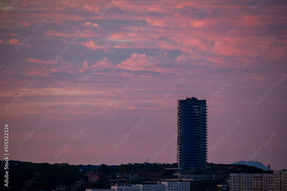 A high-rise building under construction in Vladivostok against the backdrop of a bright dawn. Construction of residential buildings.