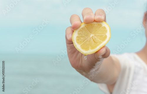 Woman squeezing lemon on the beach.  ビーチでレモンを絞る女性 photo
