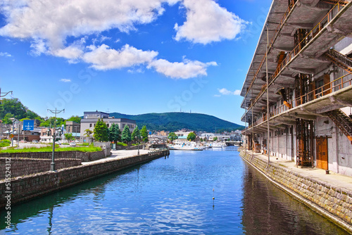 新緑の北海道小樽市、竜宮橋から見る快晴の北側の小樽北運河の街並みと係留されたクルーズ船