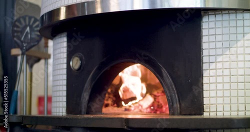 Putting a pizza into a woodfire pizza oven with a pizza peel