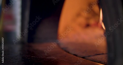 Close-up of putting a pizza into a woodfire pizza oven with a pizza peel