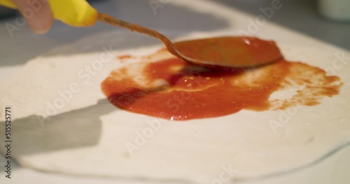 Close up of adding sauce to pizza base preparing pizza