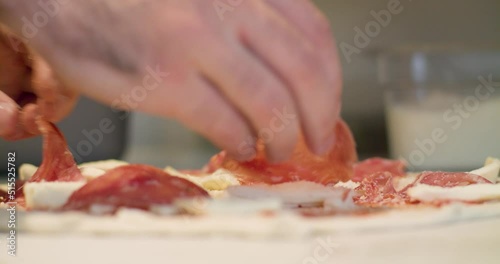 Adding pizza toppings to a pizza base with pepperoni and cheese