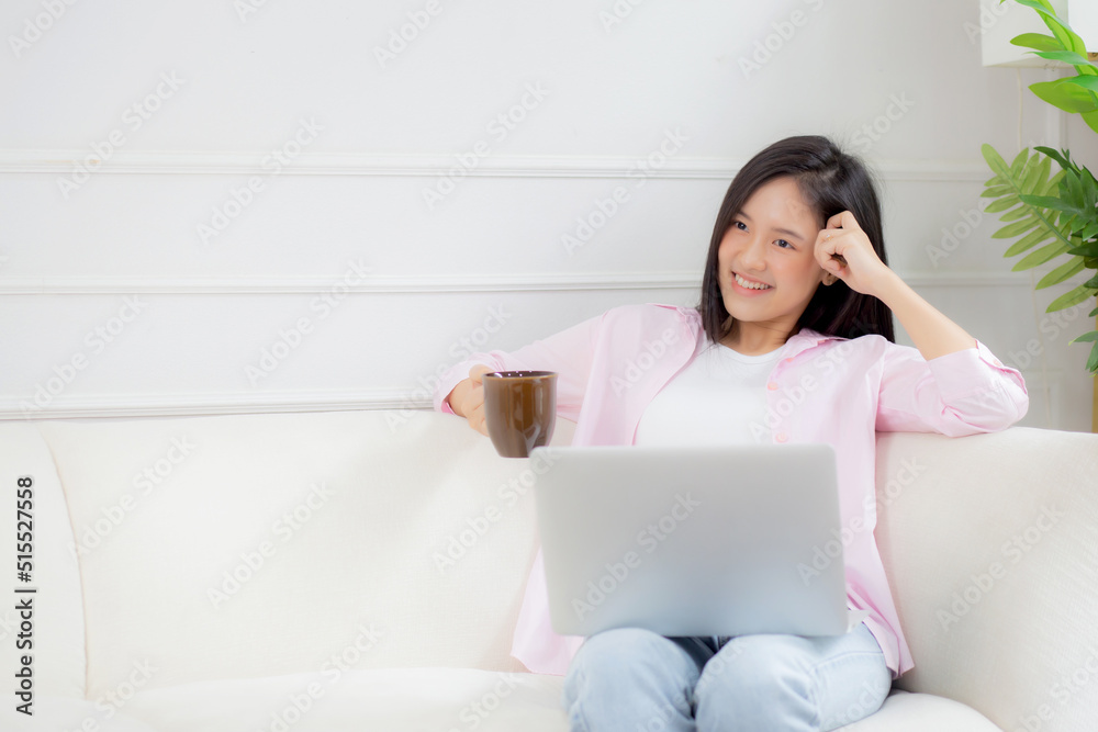 Young asian business woman work from home with laptop computer and drinking coffee on sofa in living room, freelance girl using notebook sitting on couch with comfort and relax, lifestyles concept. Young asian business woman work from home with laptop computer and drinking coffee on sofa in living room, freelance girl using notebook sitting on couch with comfort and relax, lifestyles concept.