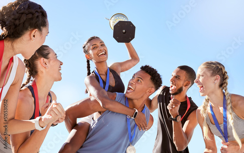 Group of a young fit diverse team of athletes celebrating their victory with a golden trophy. Team of active happy athletes rejoicing after winning an award or trophy after a competitive race photo