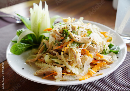 Shredded chicken salad with carrots and green papaya well presented on a plate photo