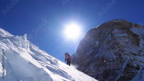 Climber reaches the summit of mountain peak. Climber on the snow range moving forward while selfbelaying with ice axe. Success, freedom and happiness, achievement in mountains. Climbing sport concept.