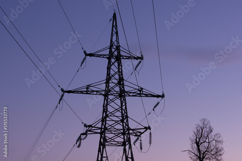 High voltage electric tower silhouette at dusk and sky on background.