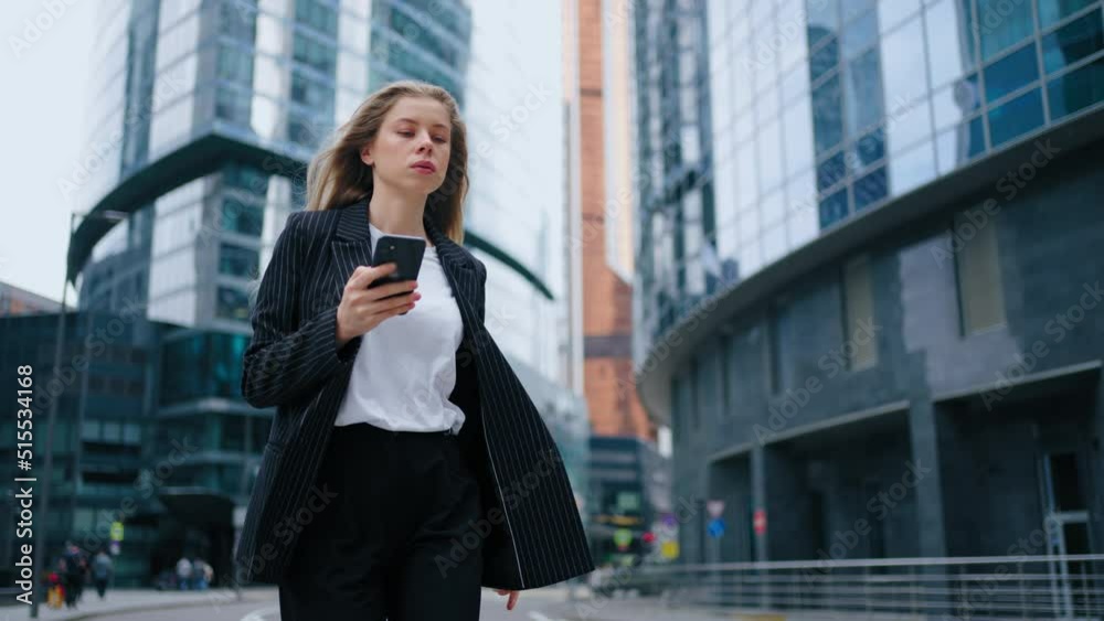 Smiling woman wearing formal suit using mobile phone typing text messages walking outside business cellphone city smartphone slow motion, outside business center Smiling woman wearing formal suit using mobile phone typing text messages walking outside business cellphone city smartphone slow motion, outside business center
