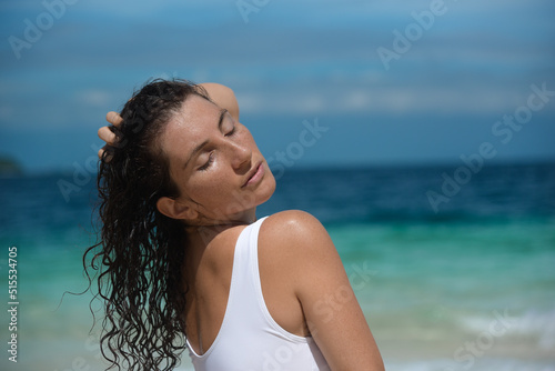A portrait of curly pretty girl in swimsuit enjoy at the sea. Beautiful female in a white bikini at the ocean. A sexy woman posing on a tropical beach during her summer holiday in the Philippines