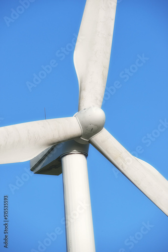 Renewable and sustainable energy generated by a modern wind turbine against a blue sky background outside. Wind energy or power generating clean electricity or mechanical power using rotating blades