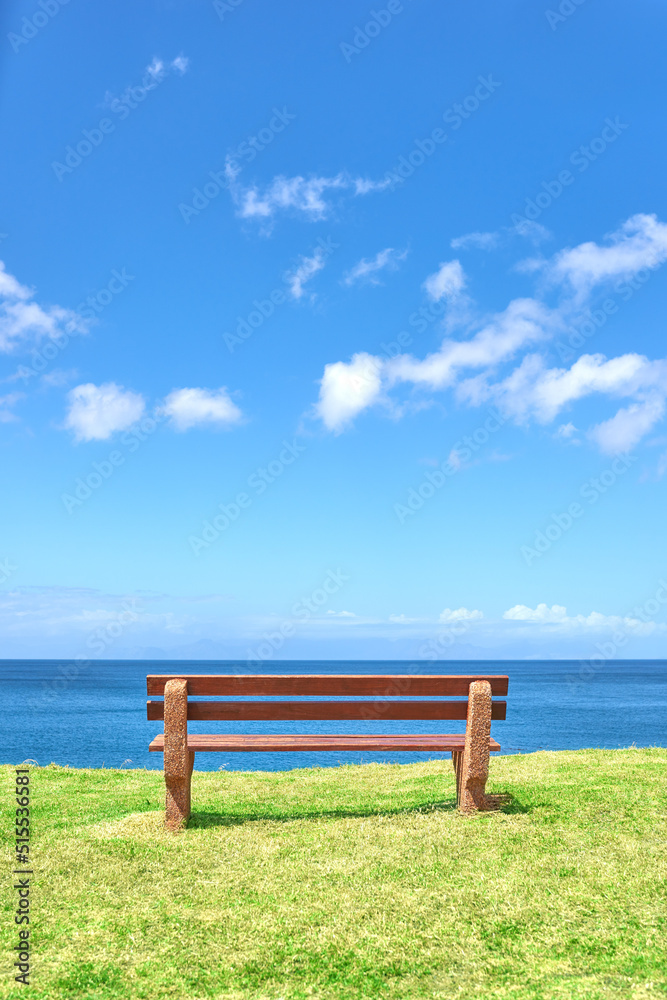 Beautiful beach view from a bench with copy space on a summer day with a blue sky background. Peaceful and calm seascape with a seat in a coastal vacation location. Scenic land of sea or ocean shore