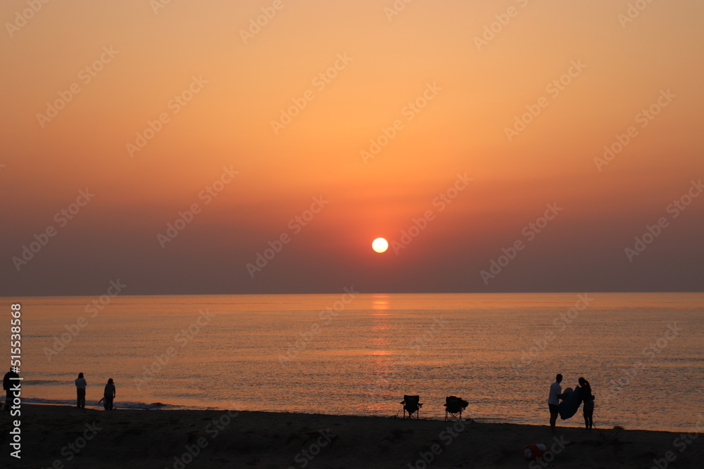 海に沈む夕日を見てテントをたたむ人々 海に沈む夕日を見てテントをたたむ人々
