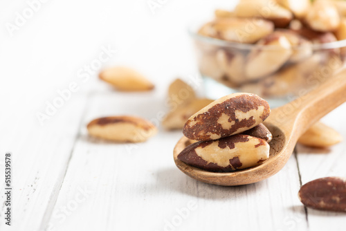Brazil nuts on wood spoon and space for text on white wooden background,