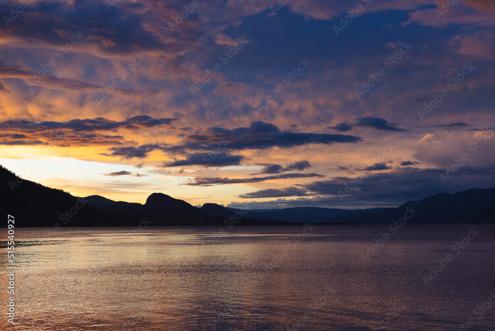 Scenic view of colorful sunset over Okanagan Lake and mountains in June