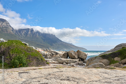 Beautiful landscape of Camps Bay in Cape Town, South Africa. Scenic mountains and rocks near the ocean or sea with a blue sky background. Peaceful nature at the beach with seascape on a summer day