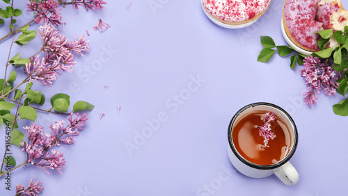 Lilac flowers with cup of tea on colourful background.