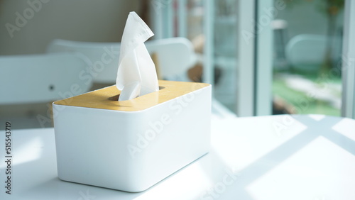 Tissue paper in napkin paper wooden white box on table. White sheet paper for cleaning face. Disposable cloth as hygienic.