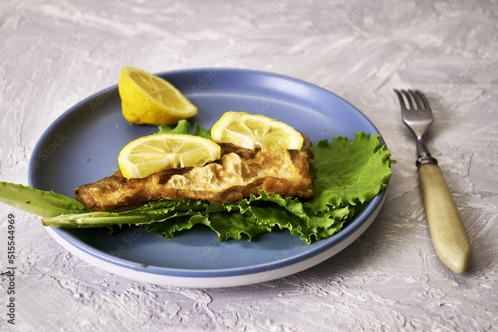 fried fish with lemon and herbs on a plate and a fork on the table fried fish with lemon and herbs on a plate and a fork on the table
