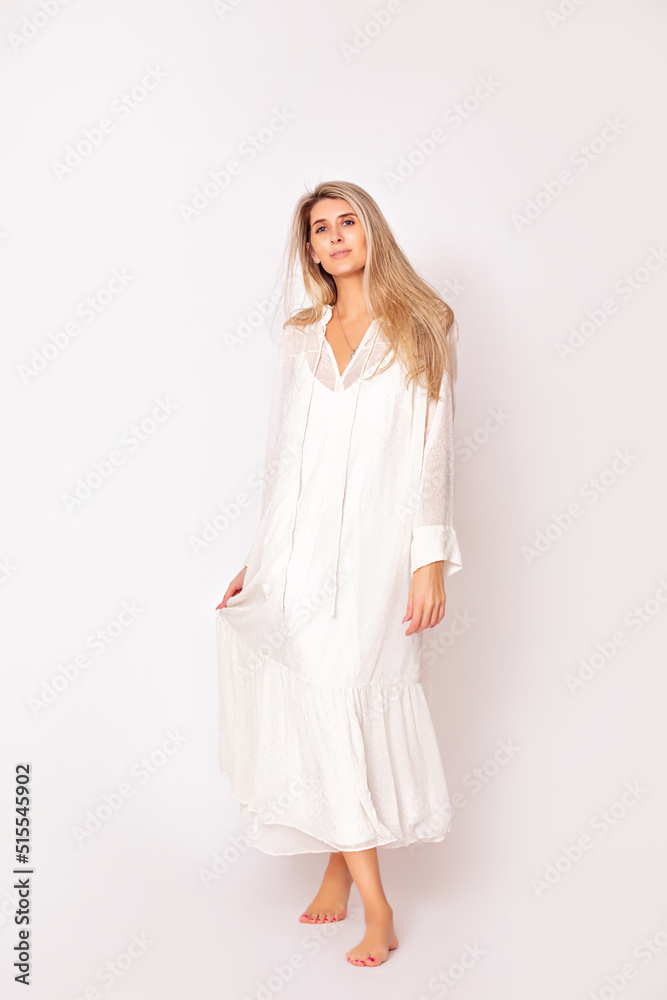 Portrait of a beautiful and young adult model of a blonde woman in a white dress on a white background. Studio shot.